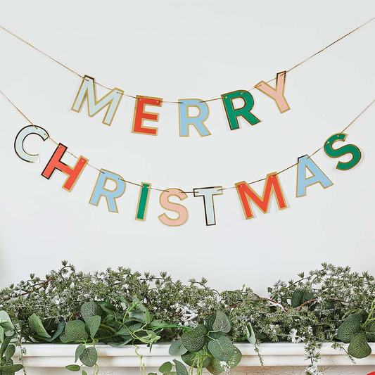 Colorful 'Merry Christmas' banner with greenery at the bottom on a white background