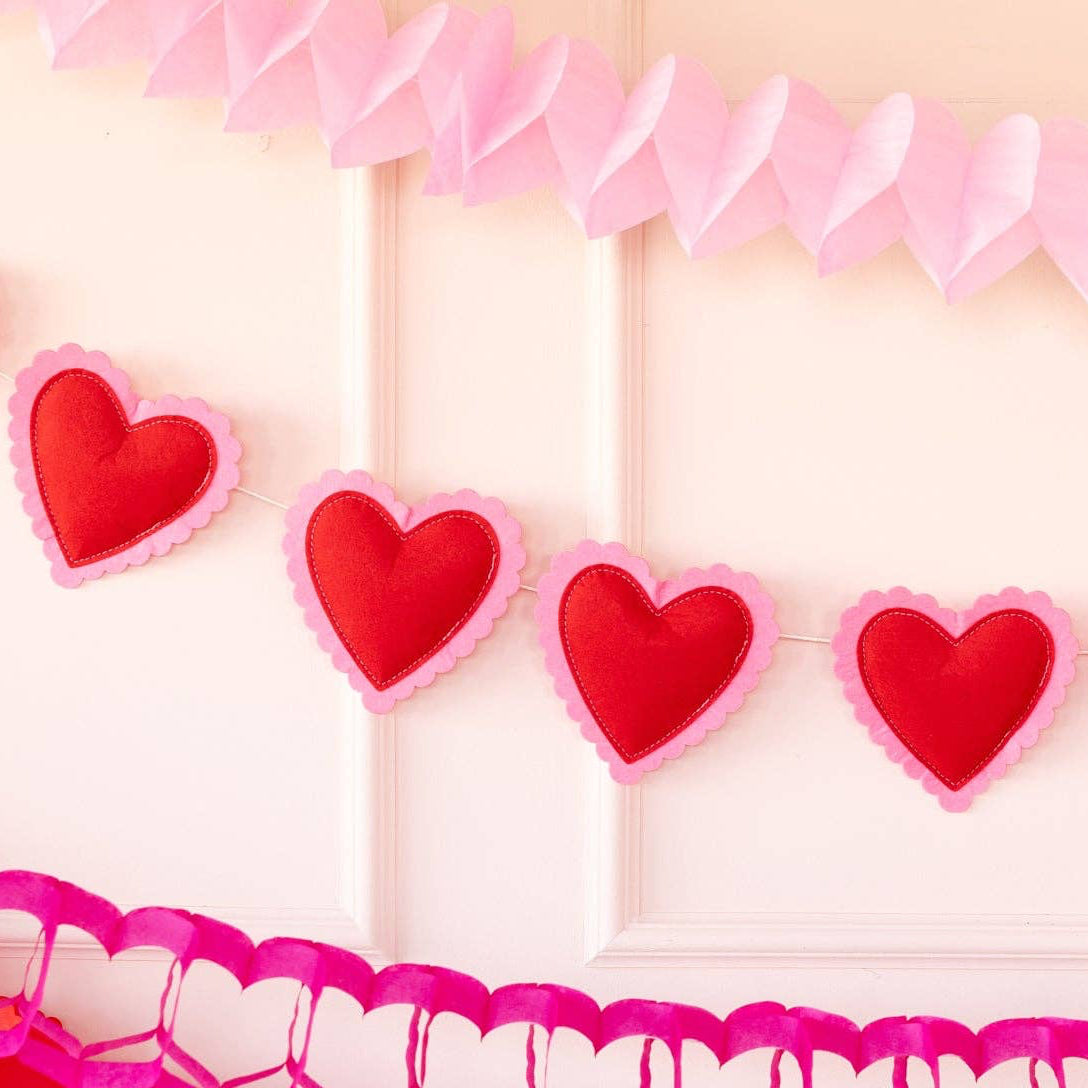 Decorative heart-shaped garland with red hearts on a pink background