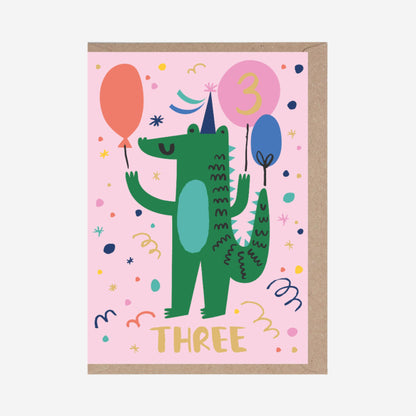 Children's birthday card with a green dinosaur holding balloons on a pink background