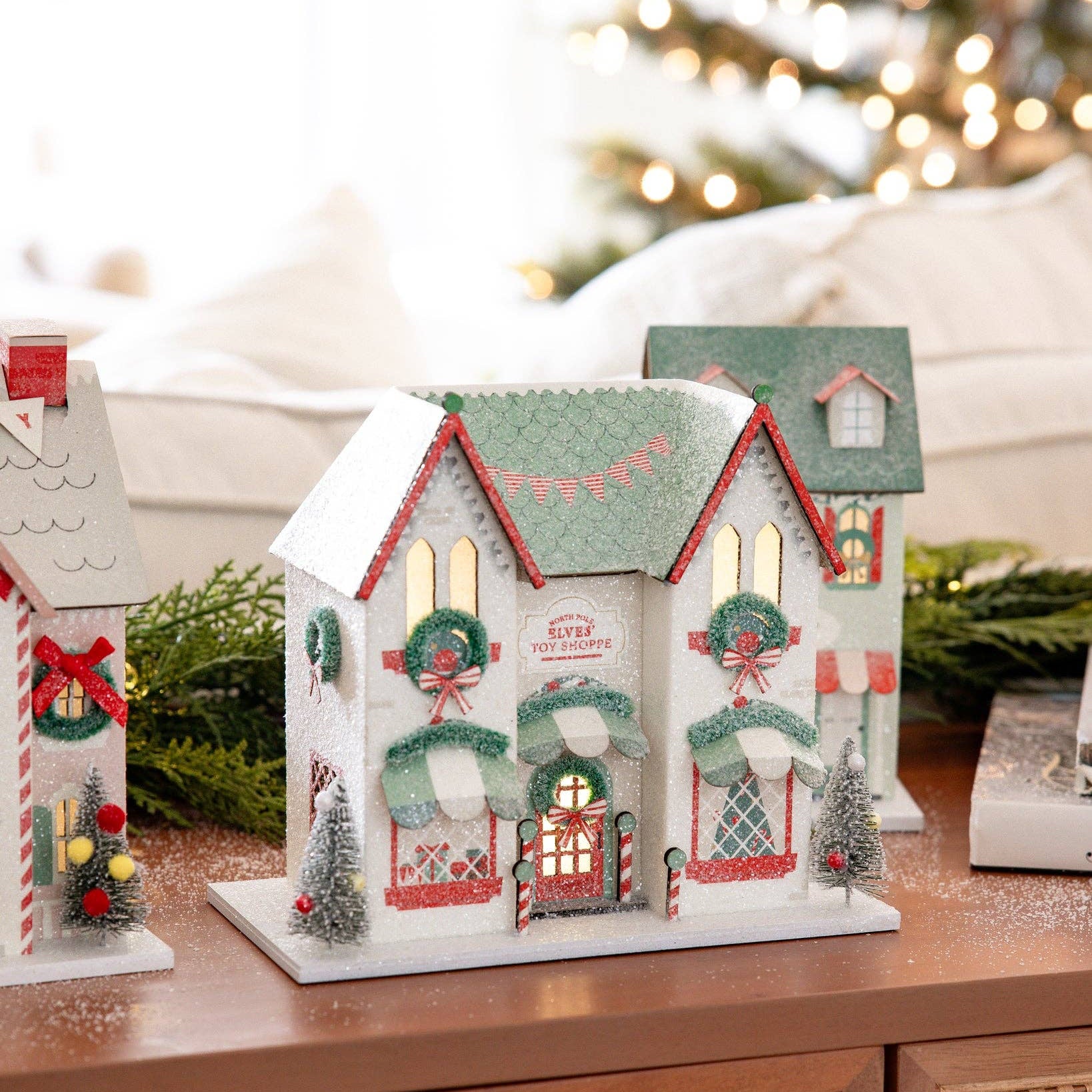 Decorative Christmas houses on a wooden surface with a blurred festive background