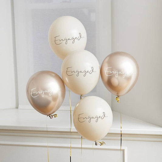 Five 'Engaged' balloons in gold and white on a neutral background