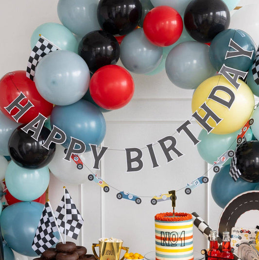 Birthday party setup with balloons, cake, and decorations in a room.