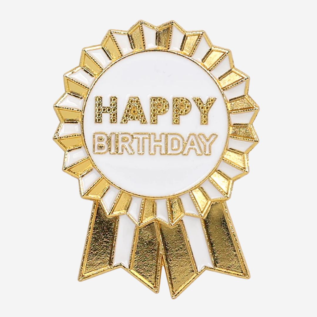 Gold and white 'Happy Birthday' enamel ribbon badge on a white background