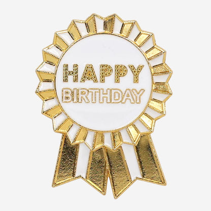 Gold and white 'Happy Birthday' enamel ribbon badge on a white background