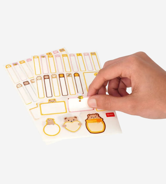 Hand holding a sheet of decorative stickers with animal designs on a white background