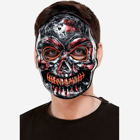 Person wearing a black and red skull mask with orange accents on a white background