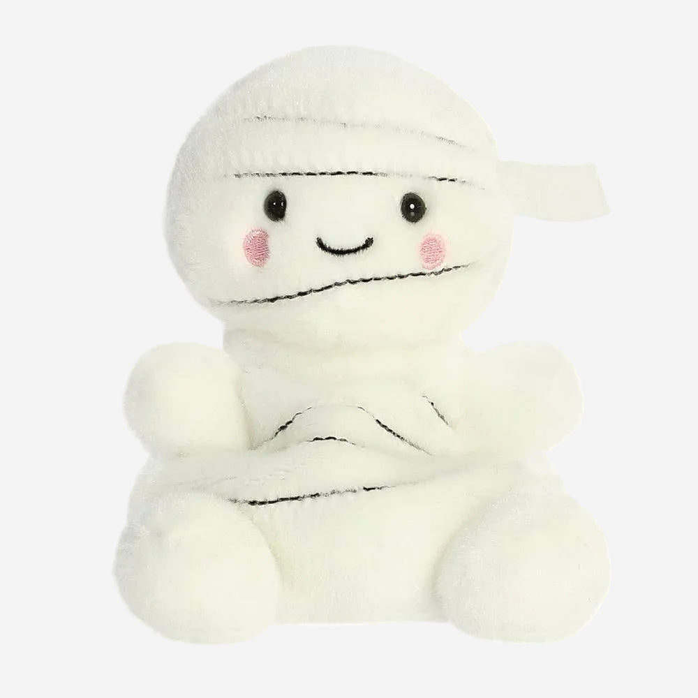 A white plush mummy toy with embroidered black stitched details, small black eyes, pink cheeks, and a simple smiling face, shown on a plain white background.