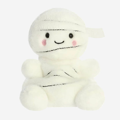 A white plush mummy toy with embroidered black stitched details, small black eyes, pink cheeks, and a simple smiling face, shown on a plain white background.